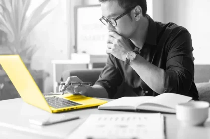 A man looking at a yellow laptop