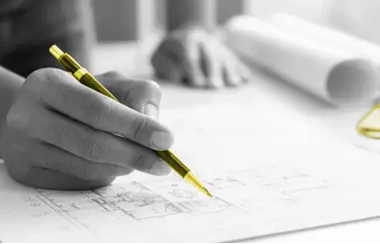 A person drawing blueprints with a yellow pen