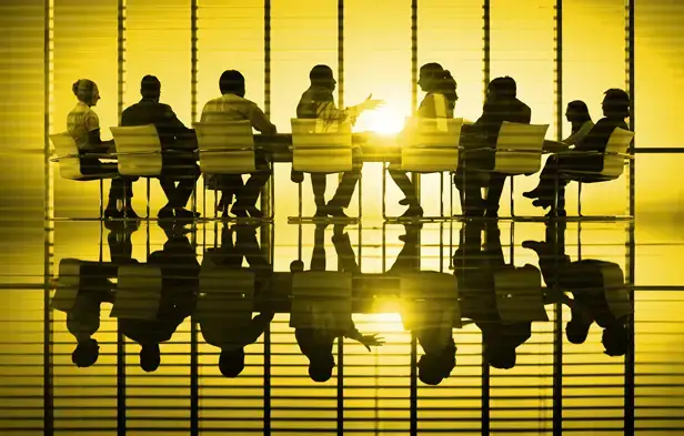Conference room meeting in a golden room with the people in shadow