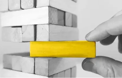 Fingers pulling a yellow puzzle piece out of a tower