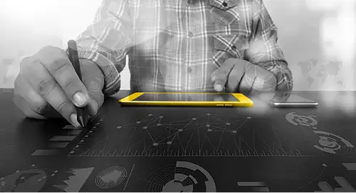 Man looking at a yellow tablet and drawing graphs