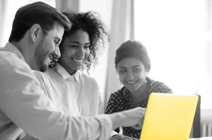 3 people looking at a yellow laptop