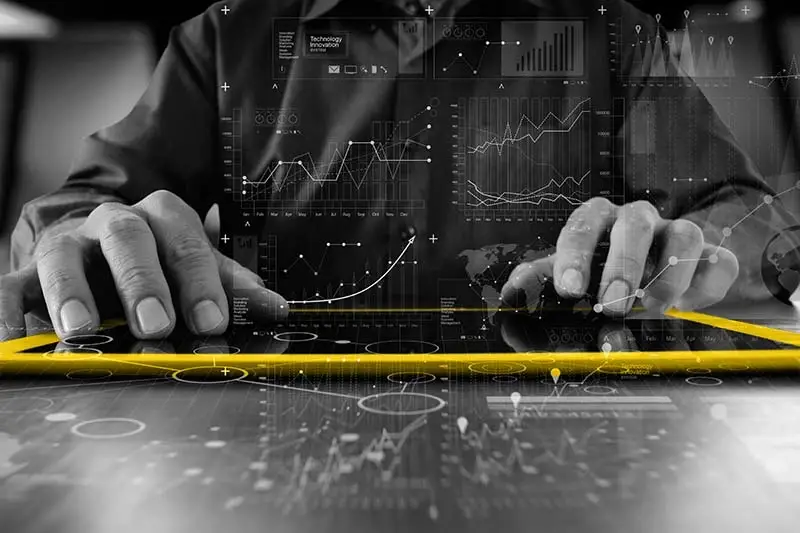 A person typing on a yellow tablet, overlaid with charts and graphs